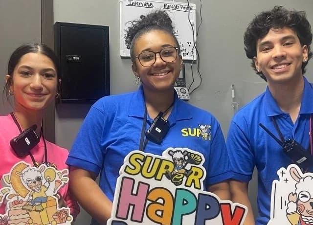Super Llama Plano team holding colorful Happy Birthday props
